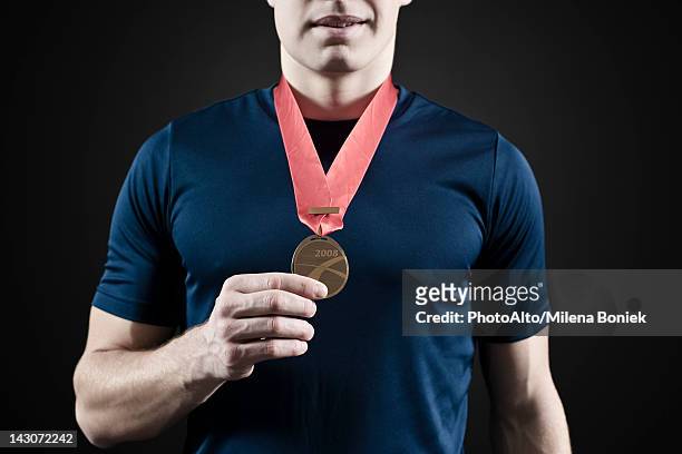 male athlete holding medal, mid section - medal of honor fotografías e imágenes de stock