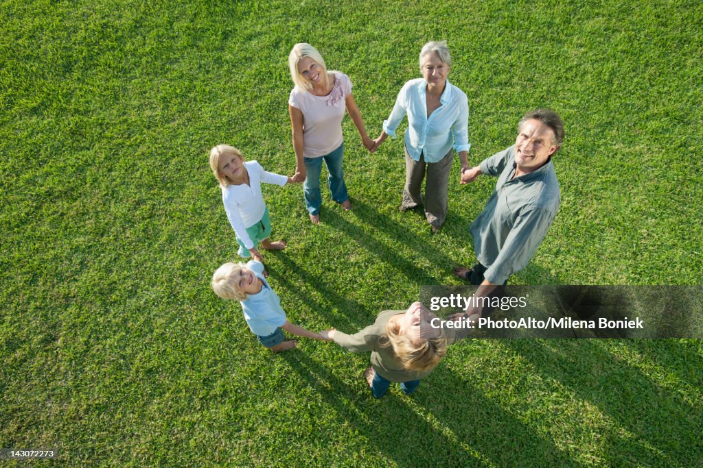 Group standing in circle holding hands looking up at camera smiling