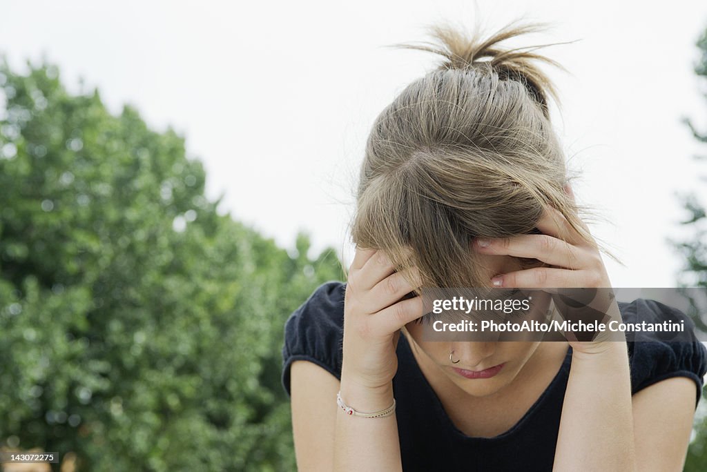 Upset young woman holding head and looking down