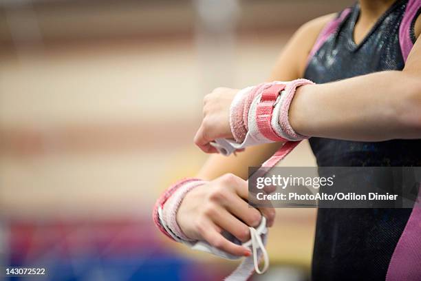 female gymnast wrapping wrists in preparation, cropped - gymnast stock-fotos und bilder