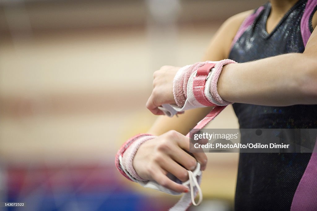 Female gymnast wrapping wrists in preparation, cropped