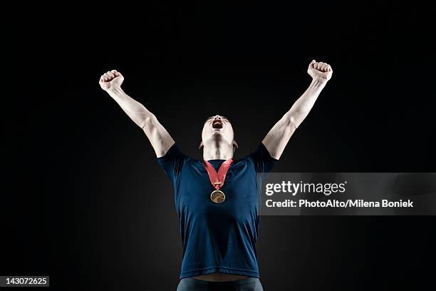 male athlete shouting with arms raised in victory - bronzemedaille stock-fotos und bilder