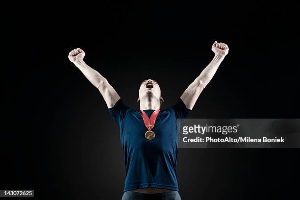 male athlete shouting with arms raised in victory - medalist ストックフォトと画像