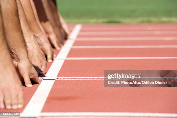 runners crouched at starting line, cropped - startblok atletiek stockfoto's en -beelden