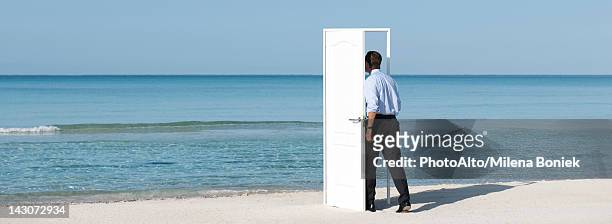 man walking into open door on beach, rear view - out of context fotografías e imágenes de stock
