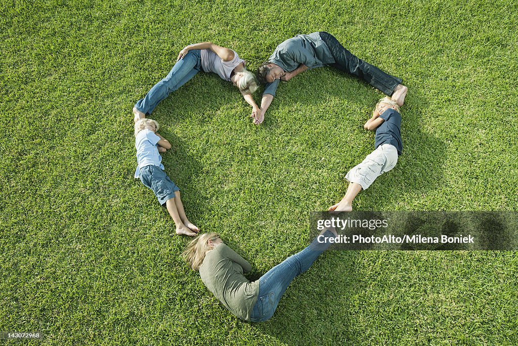 People lying on grass positioned in shape of heart