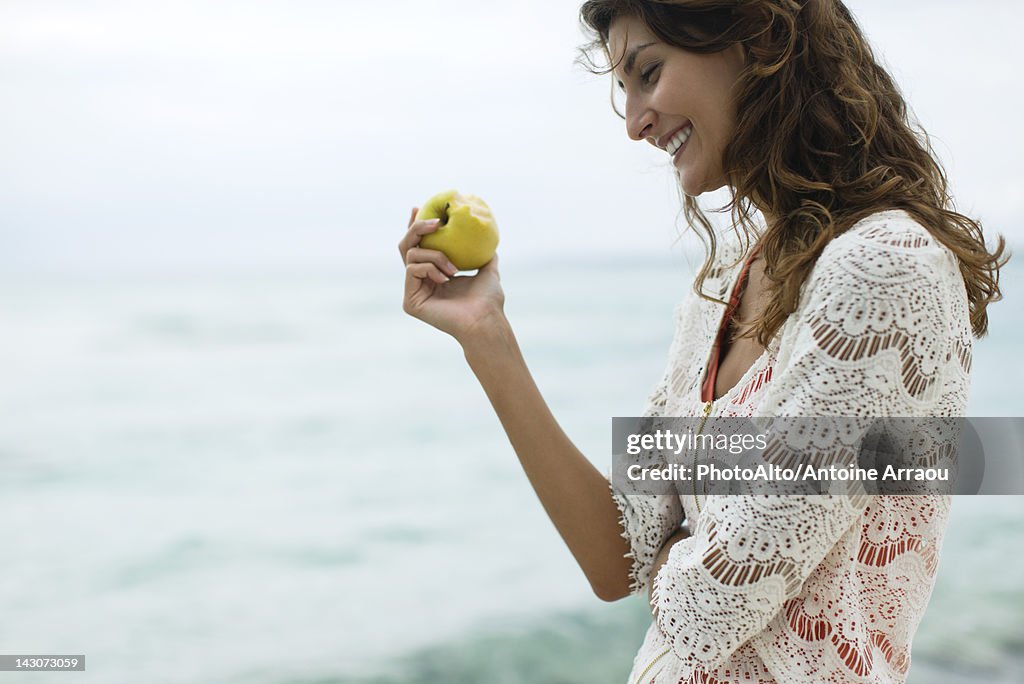 Woman eating apple at the beach