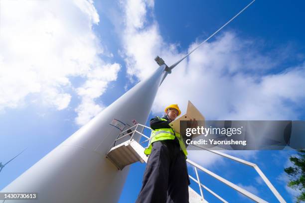 one asian young maintenance engineer man working on wind turbine farm - green economy stock-fotos und bilder