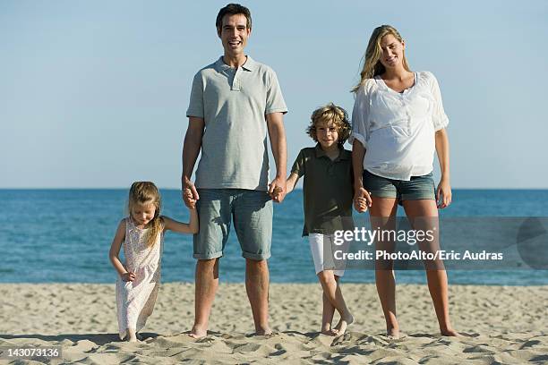family holding hands at the beach - nebeneinander-stehen stock-fotos und bilder