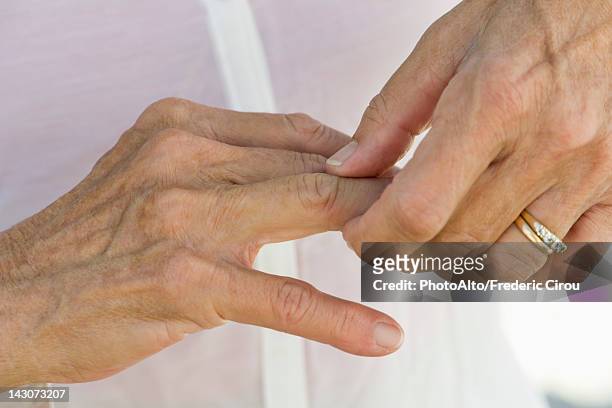 senior woman rubbing knuckles, cropped - middle finger stock-fotos und bilder