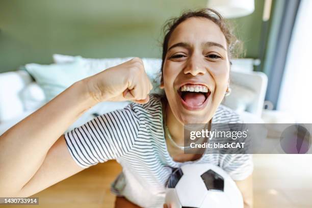 young woman watching tv and enthusiastically support her football club - club football stockfoto's en -beelden