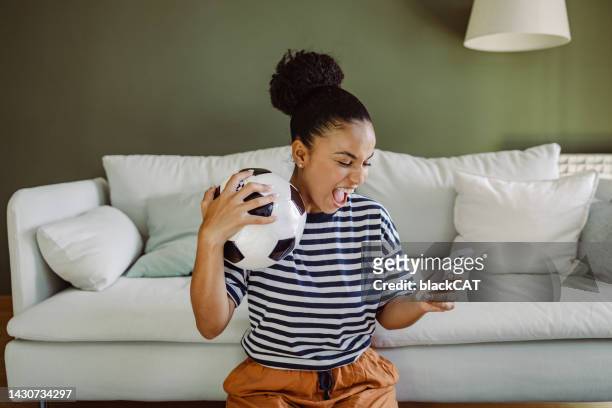 multiracial woman celebrating a goal and using smart phone - championship round one stockfoto's en -beelden