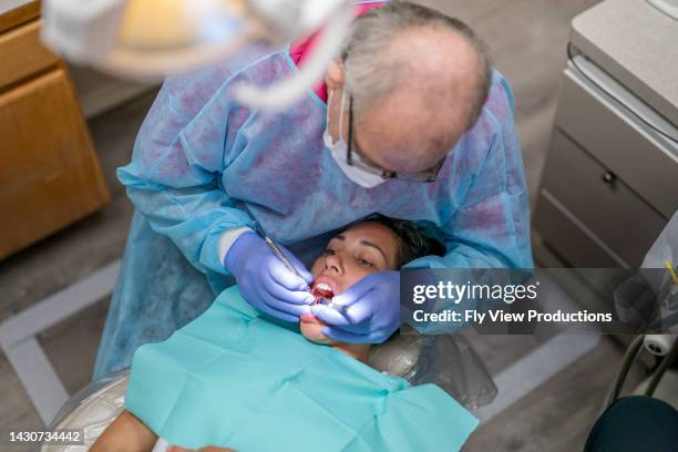 experienced dentist performing oral care for adult female patient - parodontitis stockfoto's en -beelden