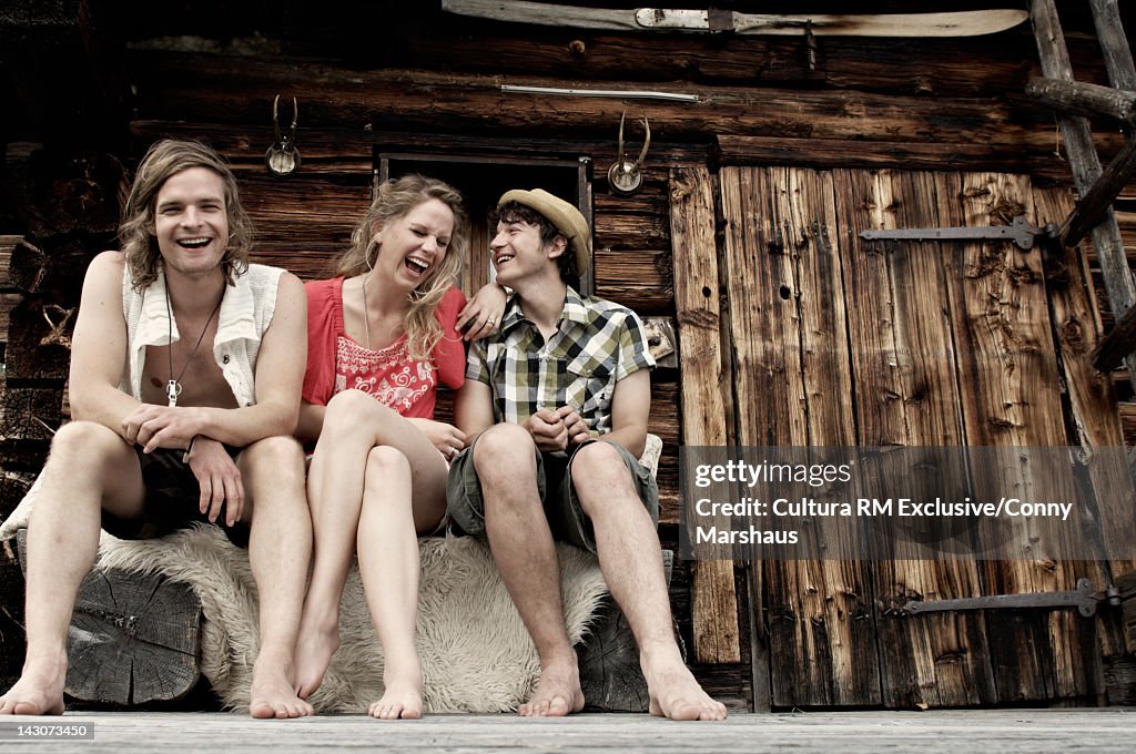 Friends sitting on log cabin porch