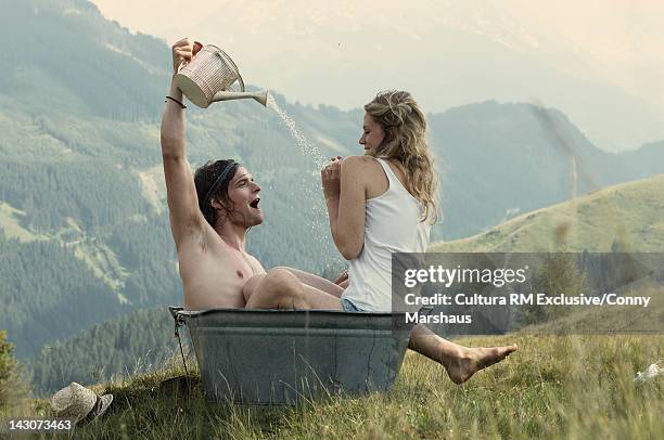 couple playing in metal tub outdoors - washing tub stockfoto's en -beelden