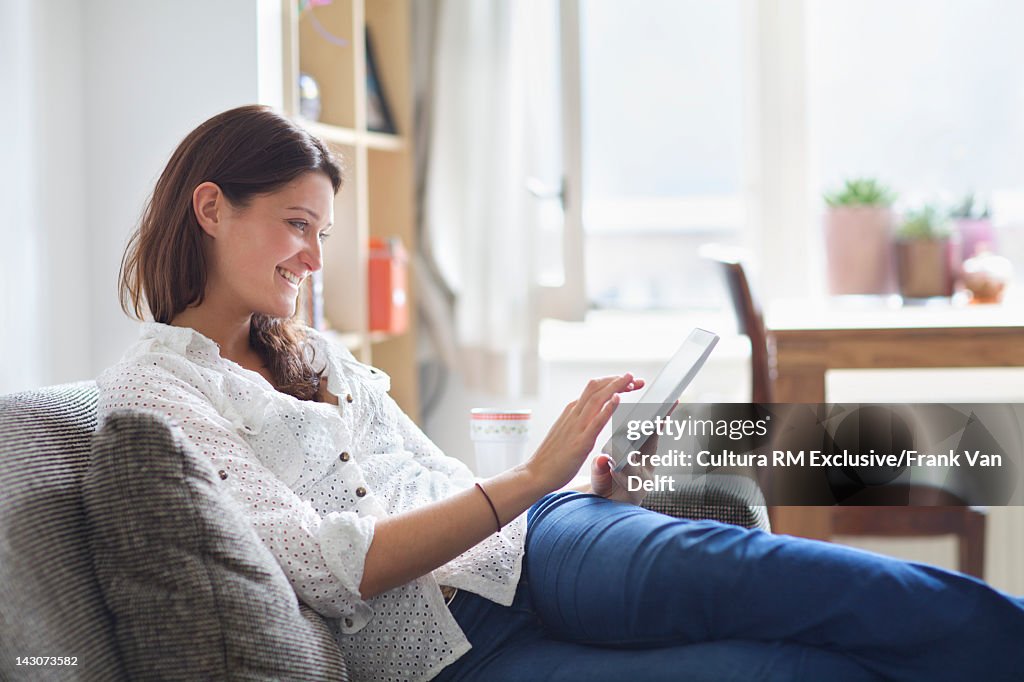 Woman using tablet computer on sofa