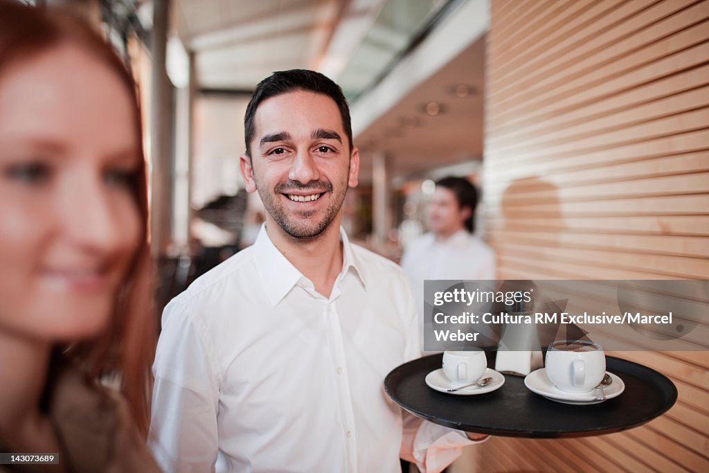 Waiter carrying tray in cafe