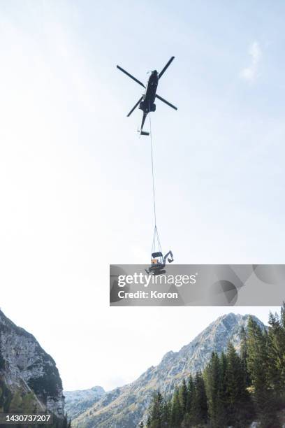 helicopter carrying load, carrying an excavator - military helicopter stock-fotos und bilder