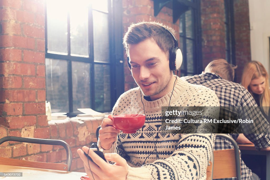 Man listening to headphones in cafe