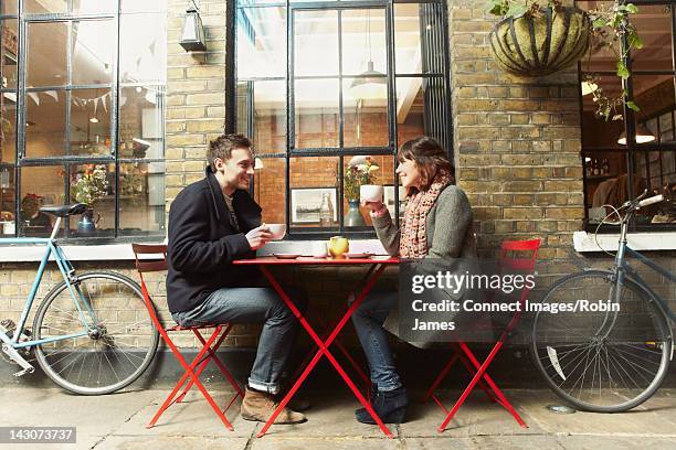 couple having coffee at sidewalk cafe - couple in cafe coffee stock pictures, royalty-free photos & images