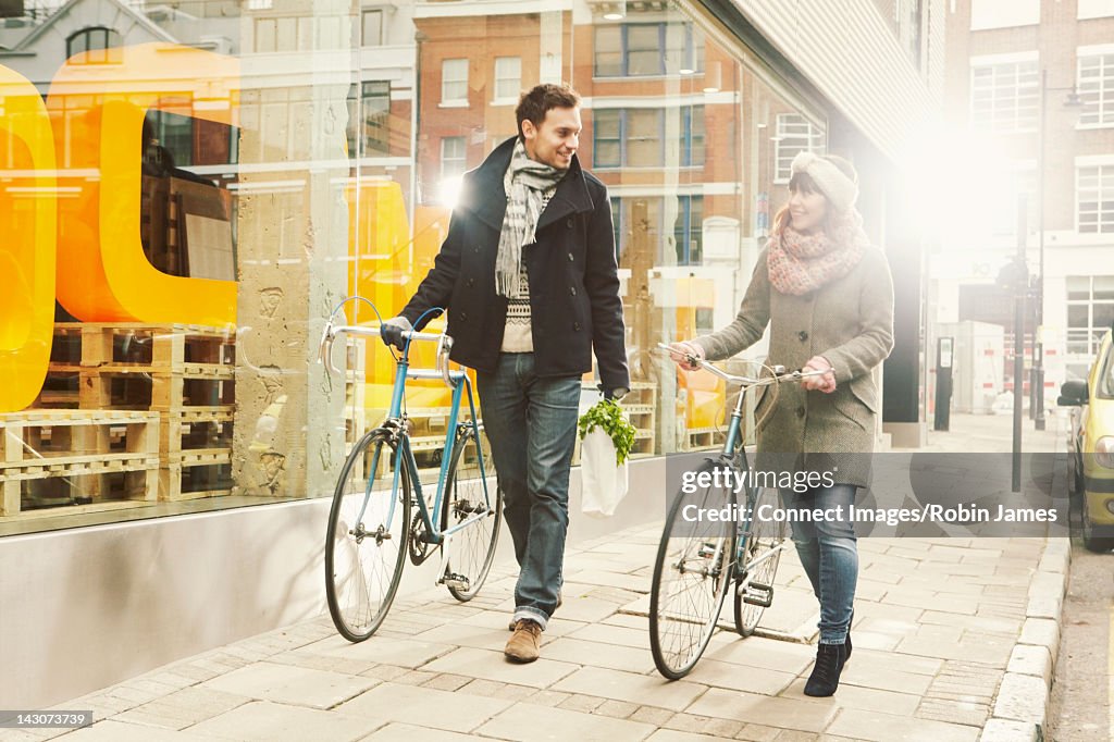 Couple walking bicycles on city street