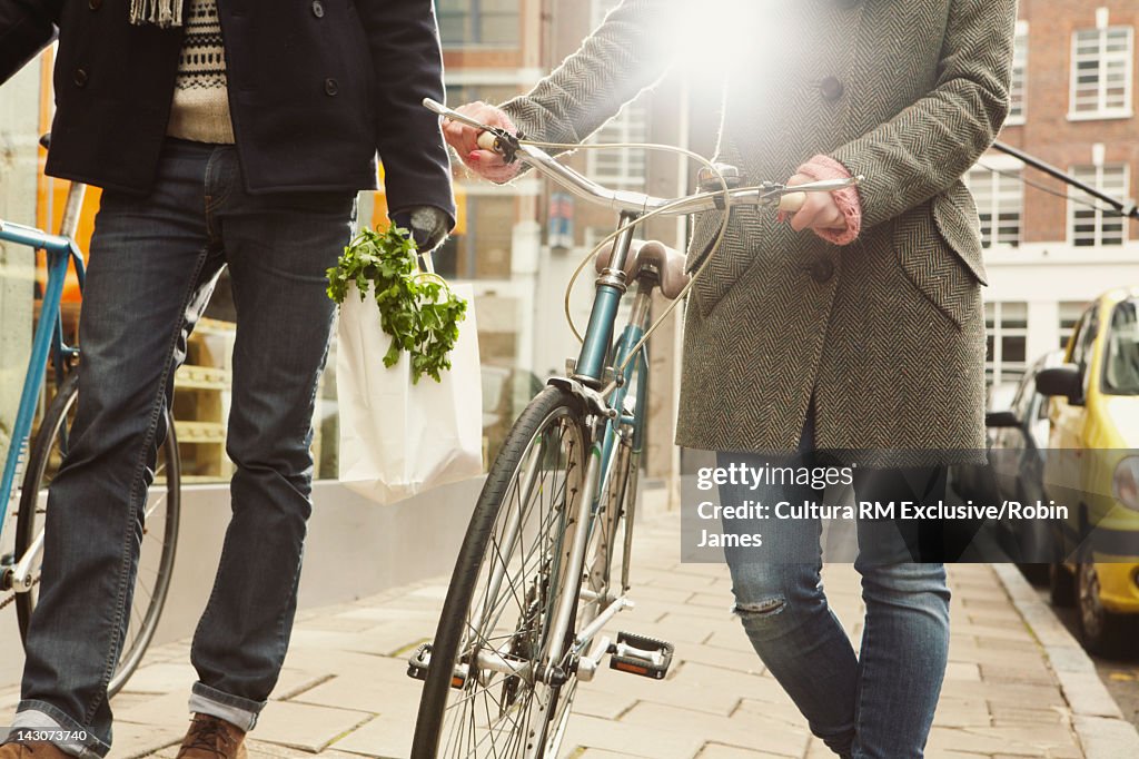 Couple walking bicycles on city street