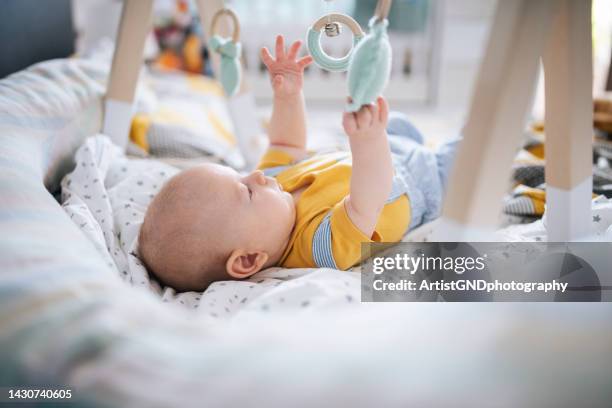 curious baby playing with wooden hanging toy. - using mobile stockfoto's en -beelden