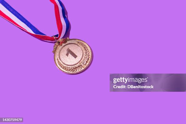 gold medal with the number 1, as the first classified, on a purple background. concept of winner, medals, honor, women's day, winning woman, working woman and sports competition. - champions awards ceremony stockfoto's en -beelden