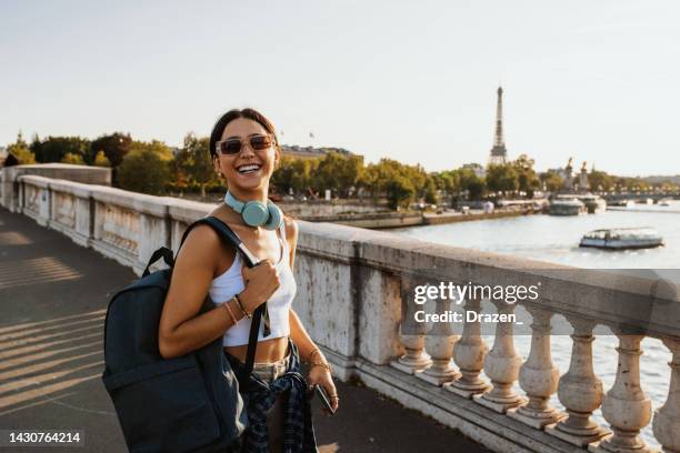 junge reisende genießen städtereise in paris im sommer, tragen rucksack und lächeln - paris millenials stock-fotos und bilder