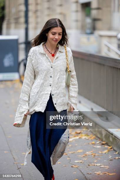 Guest wears latte button up shirt, pleated navy two tone skirt, red heels, bag, necklace outside Sacai during Paris Fashion Week - Womenswear...