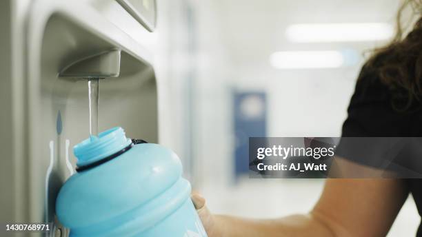 school teacher refilling a water bottle at a hallway fountain - fountain stock pictures, royalty-free photos & images