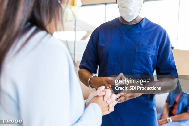woman clasps hands while receiving bad news from er doctor - receiving treatment concerned stock pictures, royalty-free photos & images