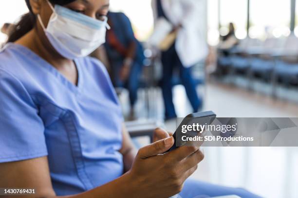 nurse in foreground text messages on smart phone - triage stock pictures, royalty-free photos & images