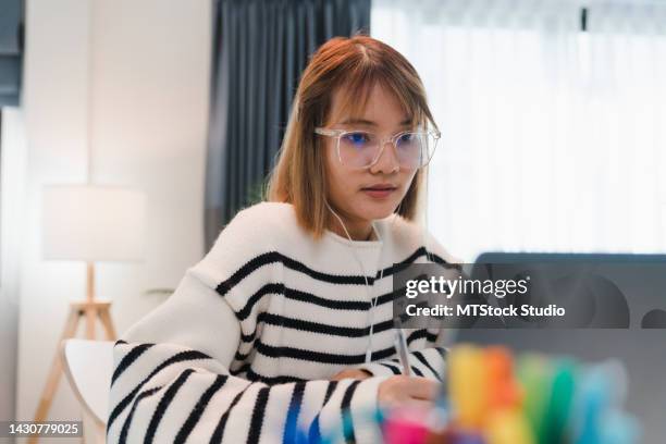 junges mädchen trägt kopfhörer mit dem laptop, lernt online und schreibt notizbuch im wohnzimmer zu hause. - student high school stock-fotos und bilder