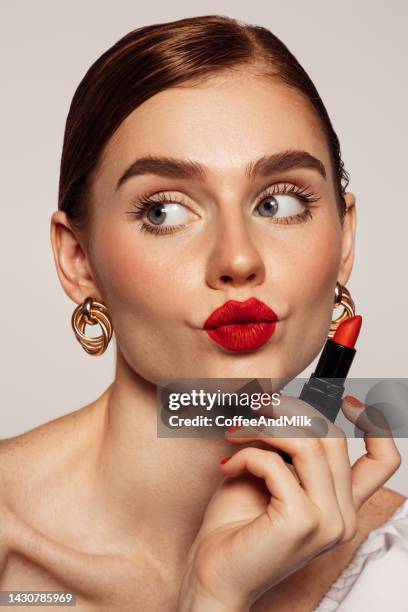 hermosa mujer emocional con maquillaje brillante aplicando lápiz labial rojo - pintalabios fotografías e imágenes de stock
