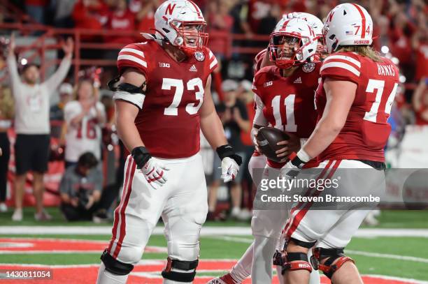 Quarterback Casey Thompson of the Nebraska Cornhuskers celebrates a touchdown with offensive lineman Broc Bando and offensive lineman Brant Banks in...