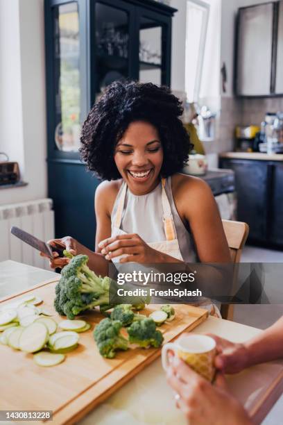 a happy mixed-race female having fun while preparing lunch - ent stockfoto's en -beelden