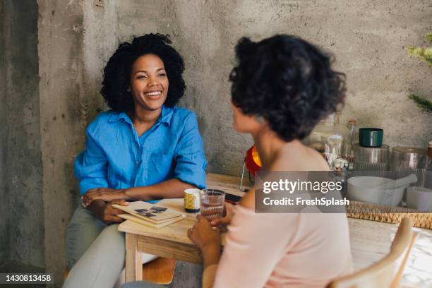 two diverse friends talking while sitting outdoors - frank wood stock pictures, royalty-free photos & images