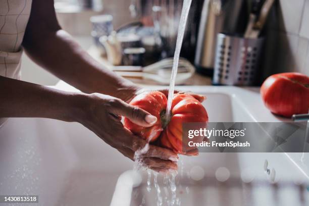 a side view of an unrecognizable woman washing a beautiful ripe - food waste stockfoto's en -beelden