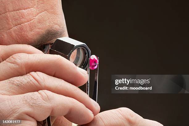 cropped image of jeweler examining jewel over black background - jewel colours ストックフォトと画像