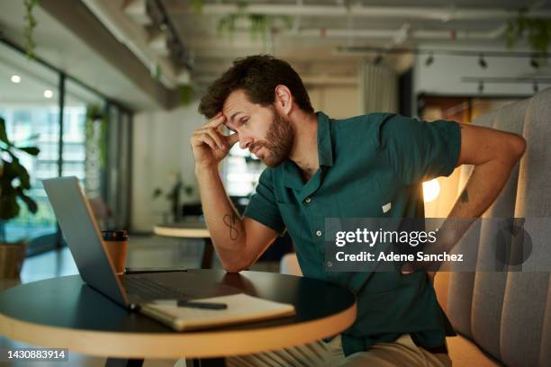 frustrated, young man with headache, back pain and burnout after a tough day. overworked male, exhausted and depressed about news or online budget planning report on his laptop in a cafe - studying hard stock pictures, royalty-free photos & images