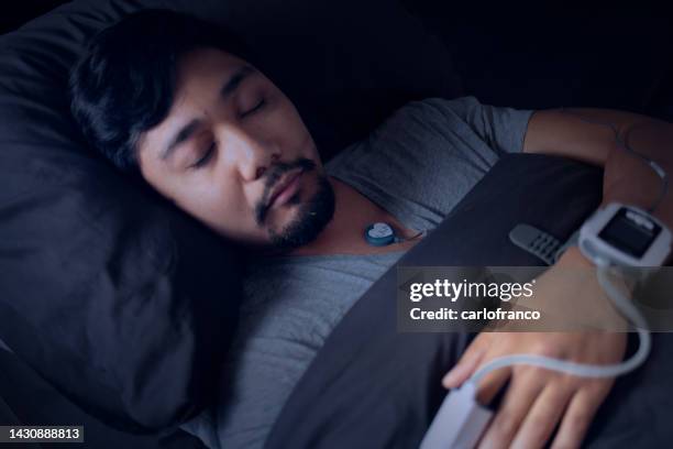 man wearing a pulse oximeter - at home sleep study test for sleep apnea - bewakingsapparatuur stockfoto's en -beelden