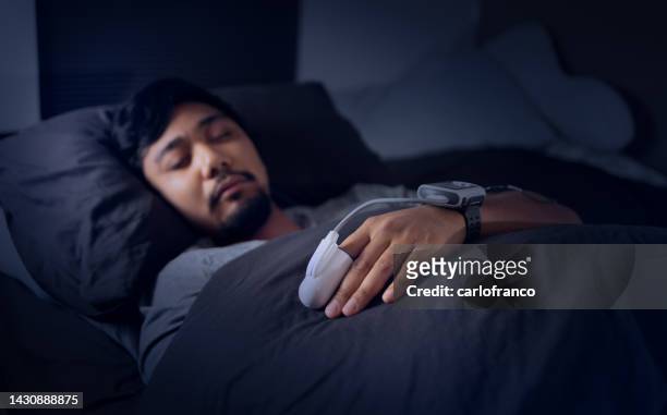 man wearing a pulse oximeter - at home sleep study test for sleep apnea - sleep apnea stock pictures, royalty-free photos & images