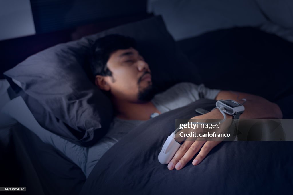 Hombre que usa un oxímetro de pulso - Prueba de estudio del sueño en el hogar para la apnea del sueño