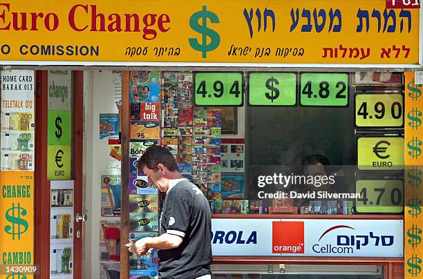 Man counts his money after exchanging U.S. Dollars at a money changer September 25, 2002 in Tel Aviv, Israel. The buy and sell rates are prominently...