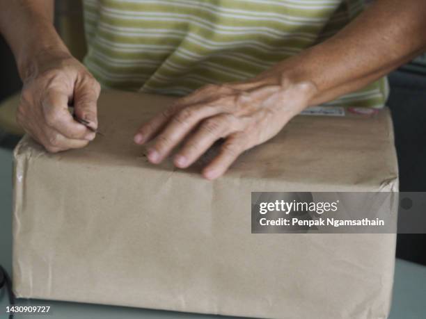 hand peeling brown paper wrapped box, damaged torn paper - torn gift stock pictures, royalty-free photos & images