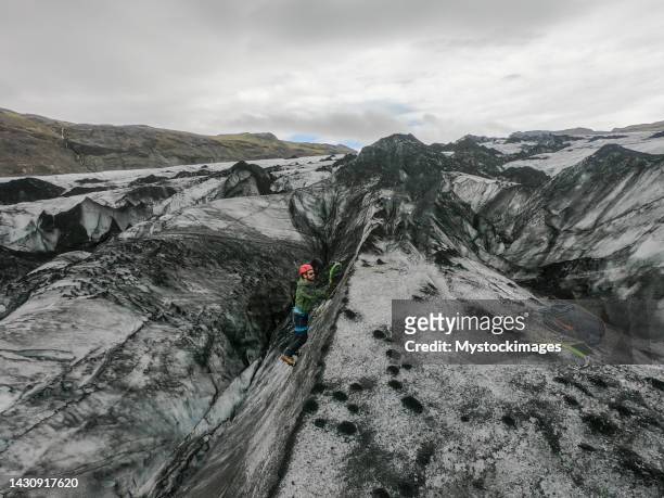 hombre escalando en hielo dentro de una grieta glaciar en islandia - crevasse fotografías e imágenes de stock