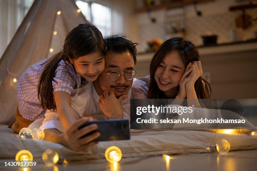 Parents and daughters enjoying the house. At night, make your own tent. and share your smartphone, take a selfie Parents and daughters enjoying the house. At night, make your own tent. and share your smartphone, take a selfie