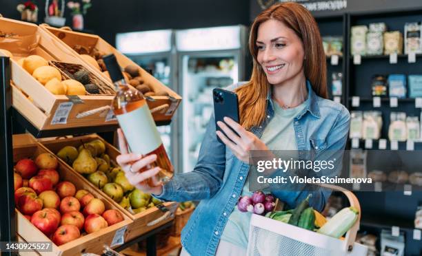 junge frau scannt barcode mit ihrem smartphone. - bio supermarkt stock-fotos und bilder