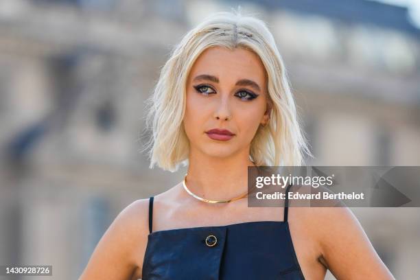 Emma Chamberlain wears a black shiny leather square-neck / buttoned long tank-top, a gold necklace, outside Louis Vuitton, during Paris Fashion Week...